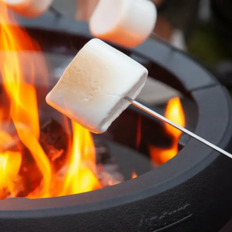Aduro Fire Ball bålpanne livsstilsbilde – sort Aduro Fire Ball uteildpanne med koselige flammer og folk som steker marshmallows på pinner hos Peisbutikken.no