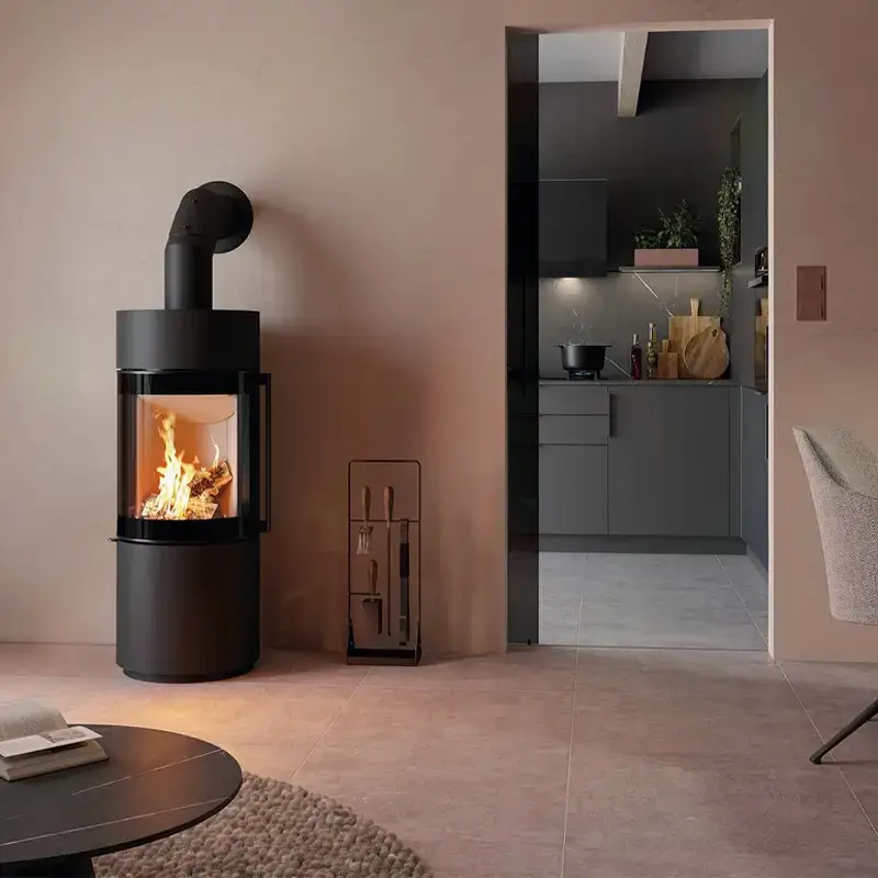 Spartherm Passo XS kompakt sort sylindrisk vedfyrt peisovn med glassfront og flammer i moderne stue hos Peisbutikken.no