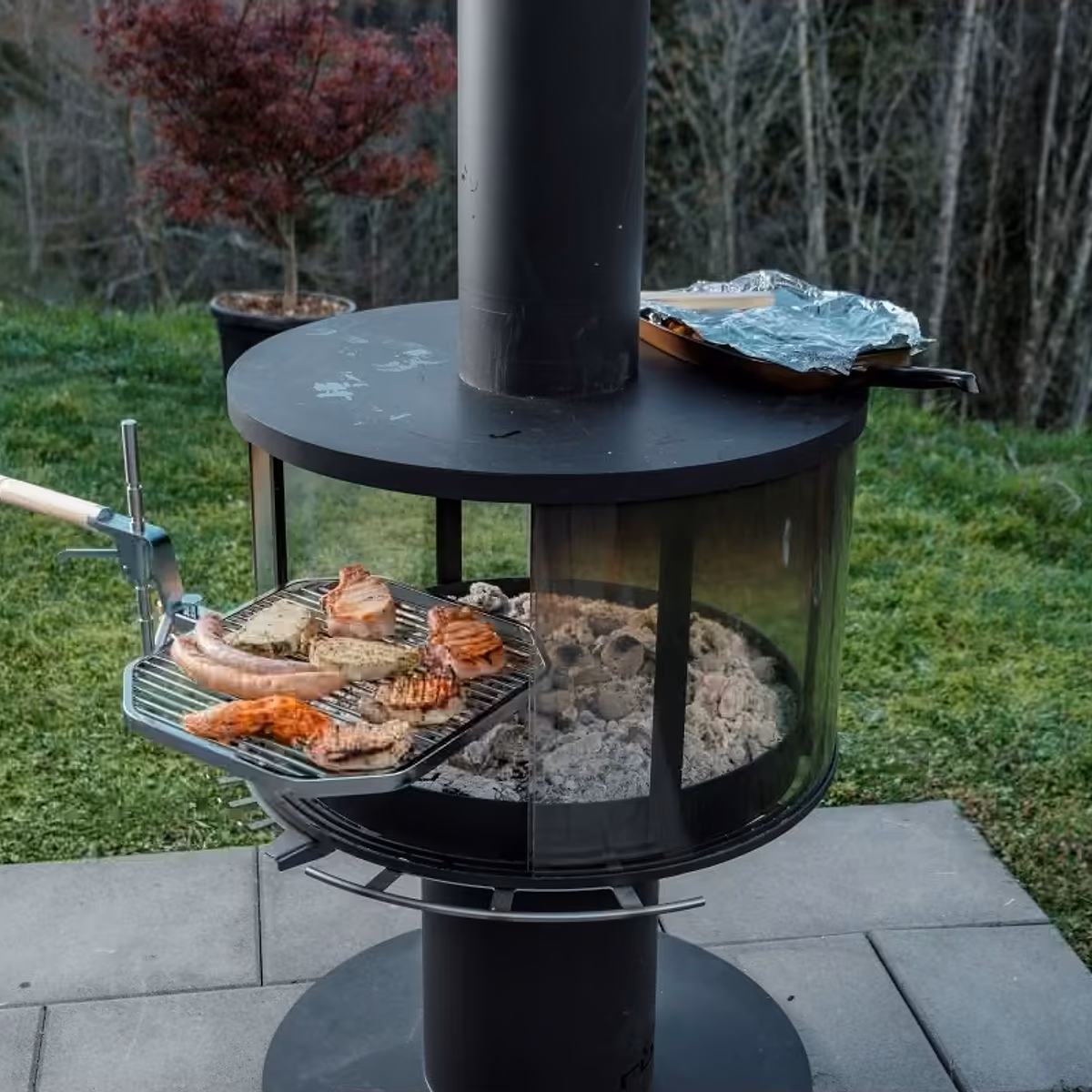 Rüegg Surprise utepeis – grilling pølser og kjøtt på svingbar grill med glødende kull i hage hos Peisbutikken.no