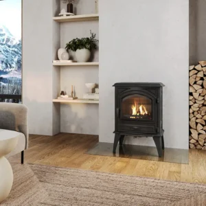 Dovre 540W vedovn i støpejern på glassplate med store flammer, omgitt av treverk og lyst interiør, med utsikt til snødekte fjell.