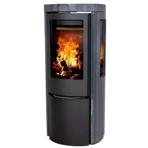 En Jydepejsen Cozy Modern Mørk Sandstein Sideglass peisovn mot en hvit bakgrunn, med en blank sort base og en teksturert mørk sandstein kropp med to sideglasspaneler og en stor forreste glassdør, som viser livlig vedfryt som brenner inni. Peisovnens sylindriske form, glatte kurver og den varme gløden fra flammene fremhever dens robuste konstruksjon og elegante peis design, og skaper et fengslende visuelt blikkfang.