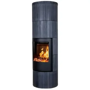 En høy, sylindrisk vedovn med en mørk sandsteinsutside og et synlig bål som brenner inne gjennom et stort glassvindu.