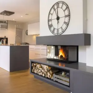 Rüegg RIII 45×68×46 peisinnsats med tre-sidig glass plassert i en romslig stue og spisestue, som gir flammeutsikt fra flere vinkler og fungerer som et elegant, varmt midtpunkt som binder sammen åpne soner i moderne arkitektur