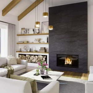 Rüegg VIOLINO 65x116 ensidig peis bygget inn i en mørk grå flisvegg, med åpne hyller og stablet ved på siden, plassert i en moderne stue med pendellamper, varme materialer og minimalistisk innredning.