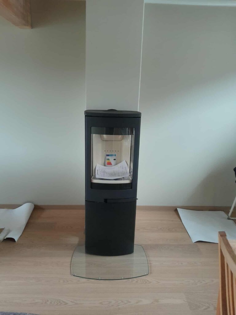 Nordpeis peisovn montert av Peisbutikken i Enebakk – moderne sort ovn med panoramaglass og vedlagring i stilig stue hos Peisbutikken.no