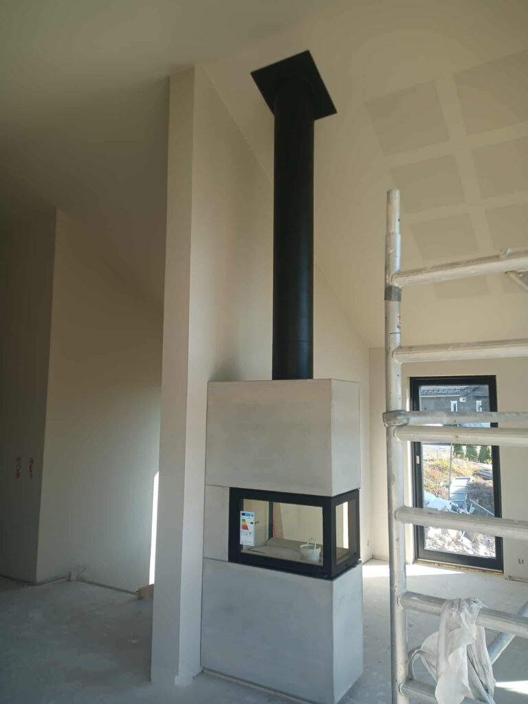 Nordpeis romdeler peis montert av Peisbutikken i Enebakk – moderne betong panoramainnsats under bygging i åpen stue